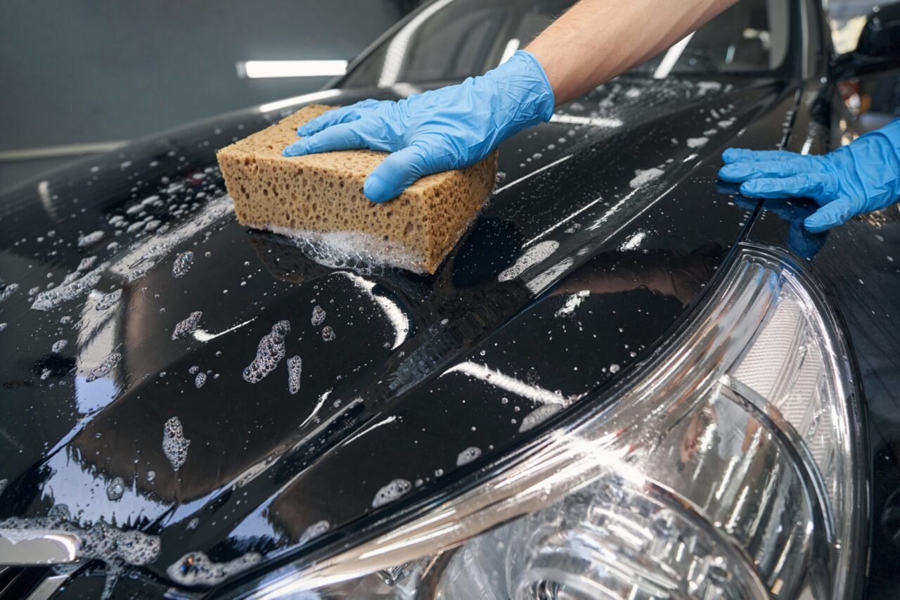 car-detailer-washing-black-vehicle-with-sponge-e1696211899164.jpg